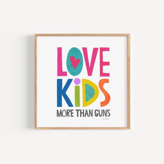 Framed poster with colorful text 'LOVE KIDS MORE THAN GUNS' on a white background